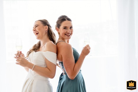 Two sisters share a joyful moment having fun together in a hotel room in Zug, Switzerland, while preparing for the wedding festivities in a lighthearted and playful atmosphere.