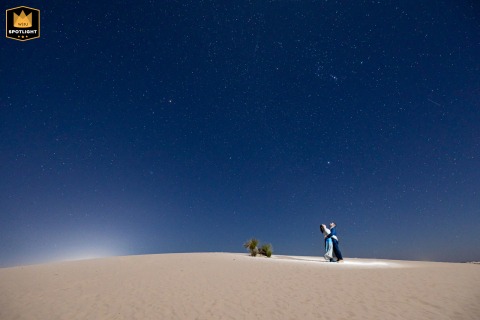 Under a vast starry sky at White Sands National Park in New Mexico, the newlywed couple gazes upward as the white dunes below reflect the glowing desert moonlight.