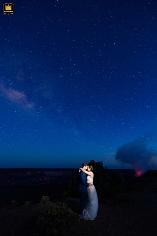 On the rim of Kilauea crater in Hawaii Volcanoes National Park, the couple share their first dance beneath the Milky Way, with red lava glowing faintly from a recent eruption nearby, creating a dramatic, unforgettable night.