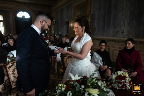 At the Comune di Borgo Carbonara Po in Mantua, Italy, the exchange of wedding rings takes place in natural ambient light, highlighting the couple’s intense focus and emotional connection during the ceremony.