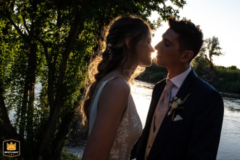 At Mulino di Massimbona in Mantua, Italy, a couple exchanges a glance backlit by the setting sun, the scene filled with intimacy as the countryside mills form a tranquil backdrop in the evening light.