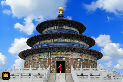 In Shanwei, Guangdong, a single woman in a red dress holds a thoughtful pose at the wedding venue, light and stillness intertwining as the day’s meaning settles, heavy with significance before the joy begins.