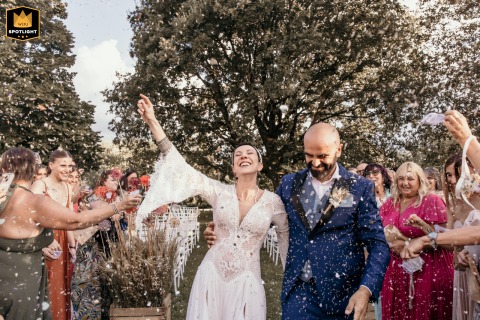 At Ca' Freschi Relais in Forlì, Italy, guests shower the bride and groom with colorful confetti, creating a vibrant and celebratory scene filled with movement and joy.