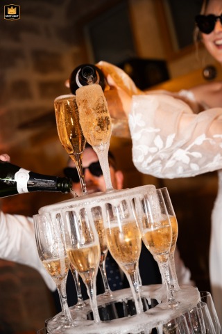In Romans, France, the celebration begins as champagne is poured into a towering pyramid of glasses, marking the start of an energetic evening reception.
