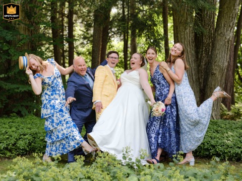 The wedding party gathers for an energetic and playful group photograph at a private home in Dublin, New Hampshire, surrounded by the natural beauty of the outdoor setting.