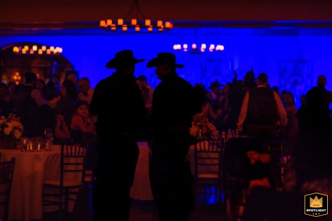 A darkened reception room at Garré Vineyard in Livermore, California, is defined by the silhouettes of two men in cowboy hats, creating a striking scene-setting image of the celebration.