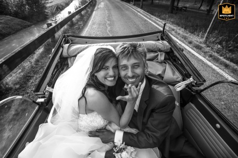 Following the ceremony at Laghi San Lorenzo in Pegognaga, Mantova, Italy, the bride and groom share a playful ride in their wedding car, creating a lighthearted and spirited image together.