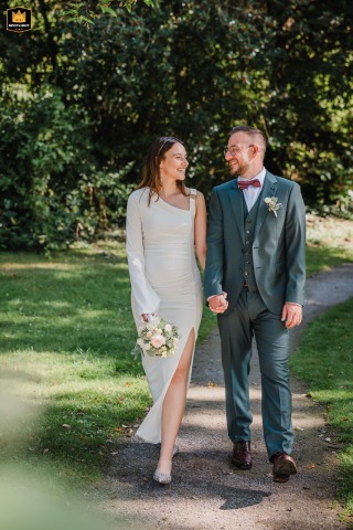 Newlyweds Stroll Through The Grounds Of Wasserschloss Haus Voerde In Germany Newlyweds walk together through the park at Wasserschloss Haus Voerde, Germany, enjoying a quiet stroll amid the grounds surrounding the historic estate.