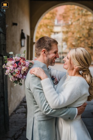 Bride And Groom Stand Beneath The Archway At Schloss Heeren In Kamen, Germany The bride and groom stand beneath the archway leading to Schloss Heeren in Kamen, Germany, framed by the historic castle entrance.