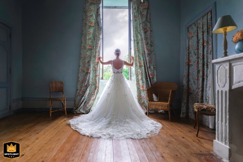 At Chateau Rossignol in Dordogne, France, the bride, fully ready, casts one last glance toward the castle courtyard before heading into her wedding day with poise.
