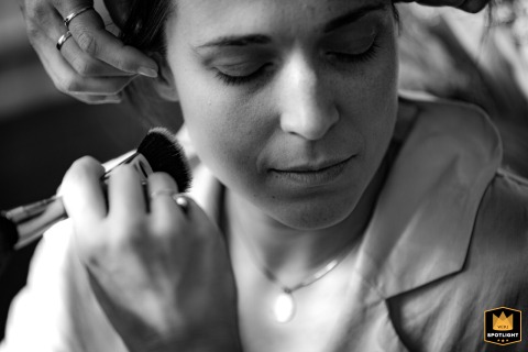 Inside Château de Crazannes in Charente Maritime, a final touch of makeup prepares the bride for the ceremony, highlighting her calm expression and elegant bridal look.