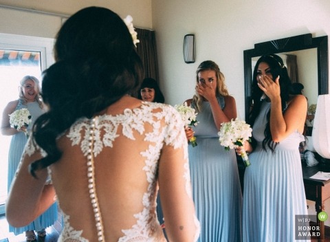 Documentary wedding photograph at a Hoi An Vietnam Hotel of the bride showing her dress for the first time to her friends, the bridesmaids