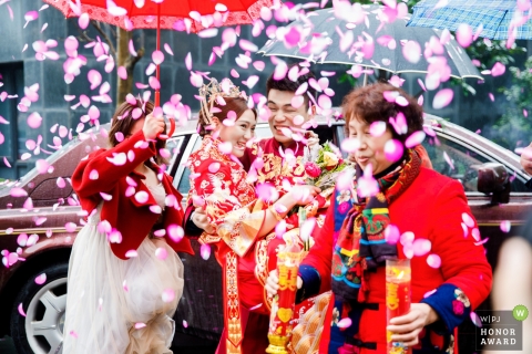 jinhua chinese tradaitonal wedding - groom carries bride under umbrella 
