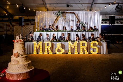 Cog Hill Country Club wedding photo of the bridal party seated for the meal under a Mr & Mrs lighted sign by the cake