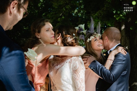 A top Paris wedding photojournalism example from a beautiful French wedding reception outdoors showing Hugs of the bride and groom with their guests 
