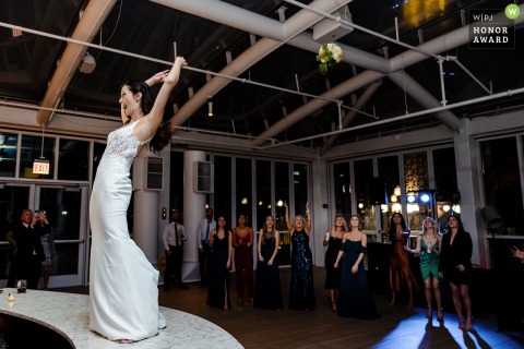 An exceptional Chicago wedding photojournalism sample by a professional Illinois photographer at the Sable Hotel at the Navy Pier communicating the bride tossing her bouquet on the dance floor 