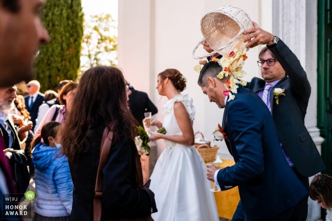 An extraordinary Udine wedding picture by a pro Italy photographer revealing the Rice toss and a basket of flower petals dumped on the grooms head