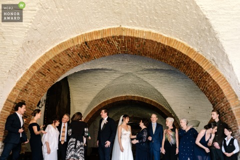 At Hacienda Vista Hermosa in Morelos, Mexico, this WPJA honor award-winning photo captures a busy scene as the family gathers under an outdoor brick and stone archway before the wedding ceremony begins.