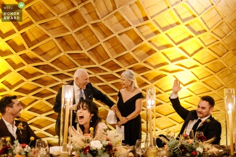 A wedding photographer captures a special moment at La Fabrica in Oaxaca City. The honor award-winning image shows the father of the bride giving a speech under a beautiful honeycomb ceiling with warm yellow tones.