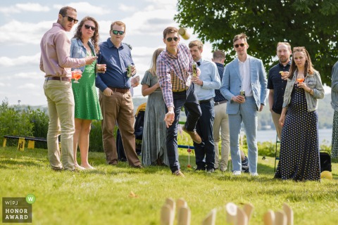 In Greensboro, VT, at Highland Lodge, wedding guests enjoy a block tossing game on the grass under the sun during the reception, adding a playful and relaxed element to the festivities.