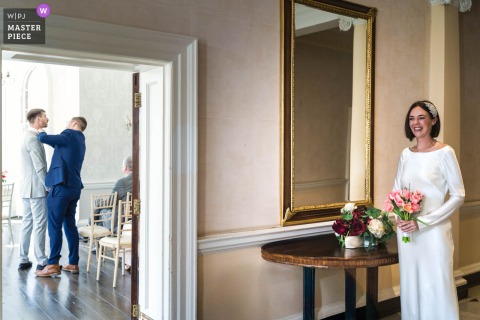 At Morden Park House, the bride stands quietly with her bouquet in hand, composed and ready just before the ceremony.