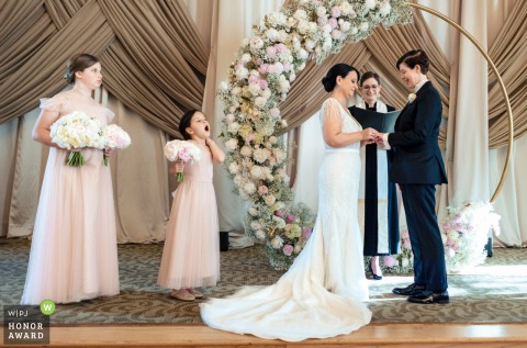 At the Biltmore Hotel in Atlanta, Georgia, a bridesmaid stifles a yawn as the couple exchanges rings, adding a candid touch to the ceremony.
