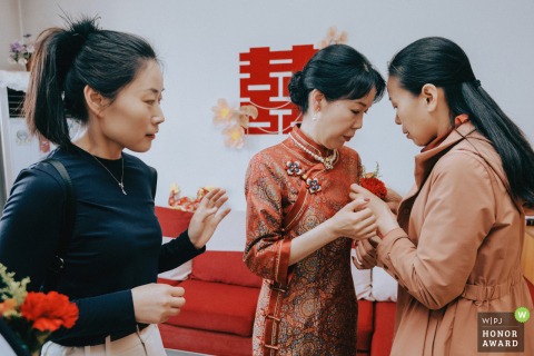 On the wedding day in Kaifeng, Henan province, family members help the bride’s mother pin on her corsage, sharing a quiet but meaningful moment together.