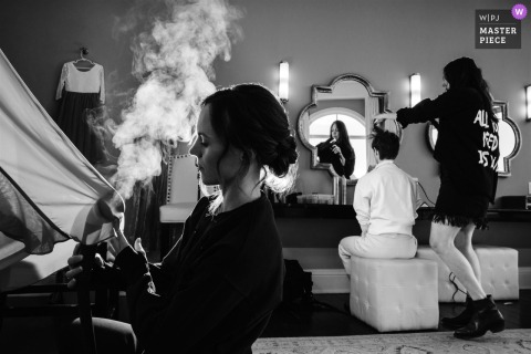 At The Pinery at The Hill, Colorado Springs, a bridesmaid steams a dress while the bride gets her hair styled.