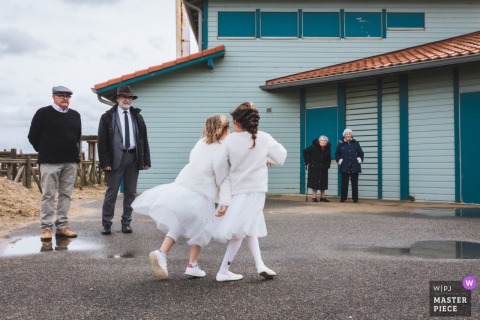 At Cap de l’Homy, France, three pairs of wedding guests from different generations stand beside the lifeguard hut, capturing ocean moments.