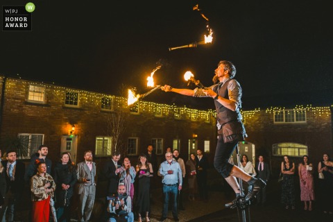 The best man entertains wedding guests with a fire juggling performance on a unicycle after dinner at Boyne Hill House, making the reception truly memorable.