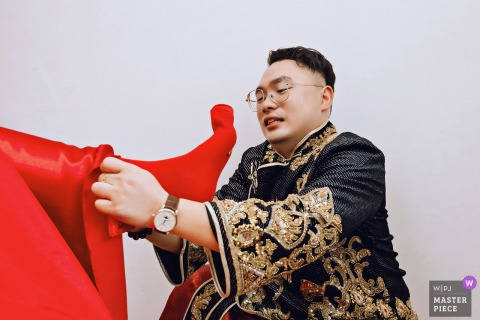In Nanping, Fujian, at home, a loved one helps gently put socks on the bride in a traditional wedding moment.