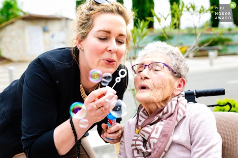 Just outside the town hall in Puycornet, a grandmother and wedding witness gleefully blow bubbles together.