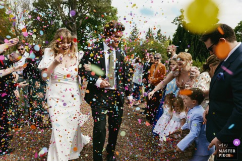 At Winton Castle in Scotland, the couple are joyfully showered with colorful confetti as they enter their wedding meal.