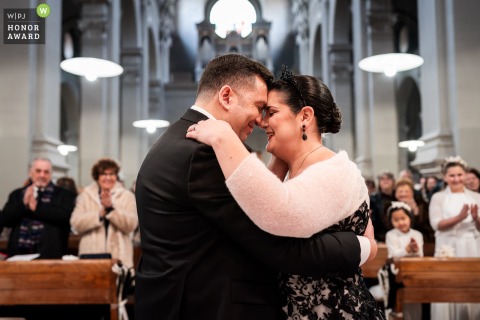 After exchanging rings, the bride and groom share a heartfelt embrace amid the elegant surroundings of a church in Trieste, Italy, savoring a quiet, newlywed moment.