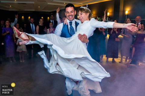 At Hotel HO Jaén, Spain, the bride and groom share their joyful wedding dance, surrounded by celebrating guests.