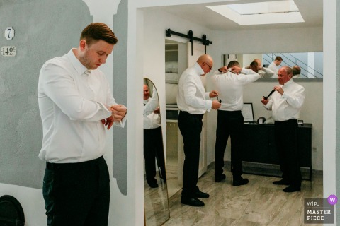 Groomsmen prepare at Domaine de la Trinité, adjusting suits and sharing laughter before the wedding ceremony.