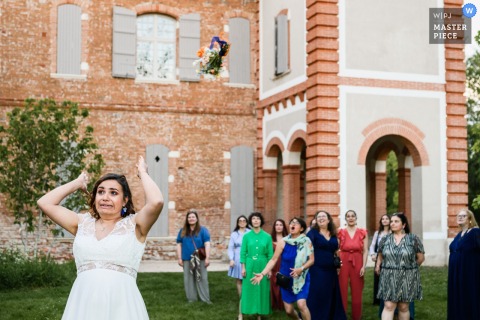 A humorous moment as the bride at Orangerie des Demoiselles makes a funny face while tossing her wedding bouquet.