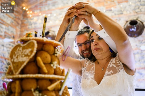 Bride and groom smiling as they cut their elegant wedding cake together at Orangerie des Demoiselles.