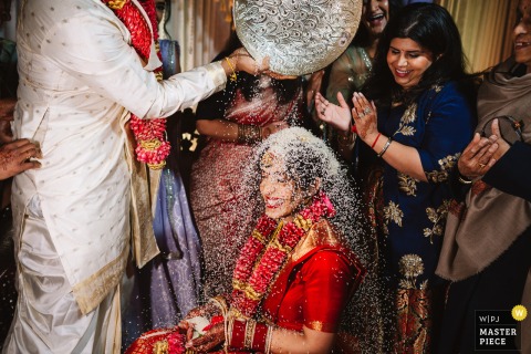 During a Hindu ceremony at Riverside on the Potomac, Virginia, guests bless the couple by sprinkling rice with joyful smiles.