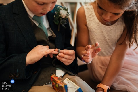 At Arnot Hill Park, the page boy and flower girl adorably try on wedding rings, creating a playful and candid moment.