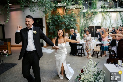 At The Ivy House in Milwaukee, the bride beams with joy during the grand march as her groom raises his fist triumphantly.