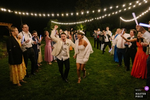 At Historic London Town and Gardens, Maryland, bride and groom in captain hats joyfully run down guest-lined aisle after ceremony.