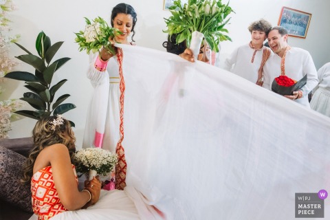 Bride and groom in Addis Ababa, Ethiopia, lovingly peek at each other during reveal ceremony at bride’s parents’ residence.