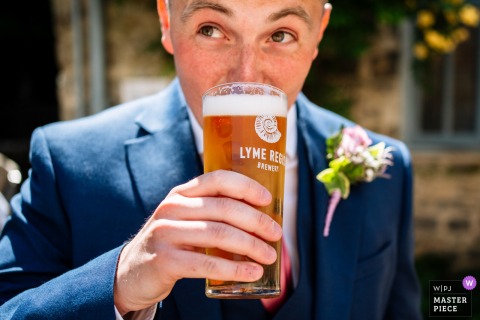 In Lyme Regis, Dorset, the groom relaxes and sips a beer, enjoying a quiet moment before his wedding ceremony.