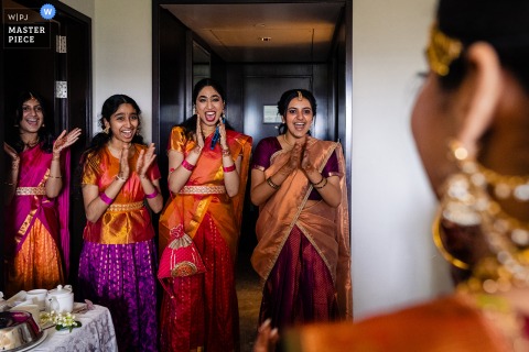 At The Taj Coromandel, Chennai, India, bridesmaids joyfully react with excitement upon seeing the bride in her wedding attire.