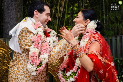 Bride and Groom Exchange Floral Garlands With Happy Smiles After Indian Wedding Ceremony in Silver Springs Maryland In Silver Springs, Maryland, the bride and groom exchange floral garlands with smiles after their Indian wedding ceremony, in the comfort of their own home.