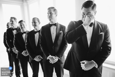  Black and white photo of groom in Charleston, South Carolina, shedding tears while watching processional, capturing raw emotion.