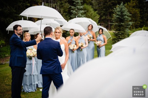 In a wooded area in Big Sky, Montana, the couple exchanges their vows during a romantic rain shower, creating a moody and atmospheric scene.