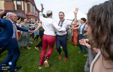 At Highfield Hall in Falmouth, the grooms dance joyfully to the Jewish folk song "Hava Nagila." The award-winning photo highlights the photographer's skill at documenting the vibrant energy and tradition of a wedding.