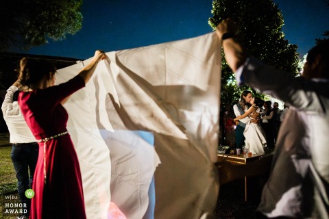 At Villa Breda in Cellatica, friends hold up a white sheet to display a special video for the newlyweds, concluding with a romantic kiss shared between the happy couple.